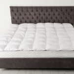 A view of a bed with a bed mattress topper on top