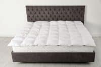 A view of a bed with a bed mattress topper on top