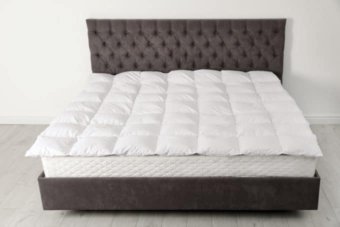 A view of a bed with a bed mattress topper on top