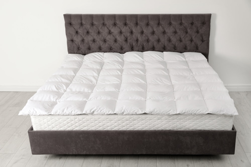 A view of a bed with a bed mattress topper on top