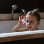 A view of a kid holding a bath bomb in shower