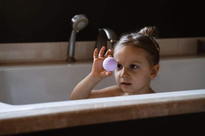 A view of a kid holding a bath bomb in shower