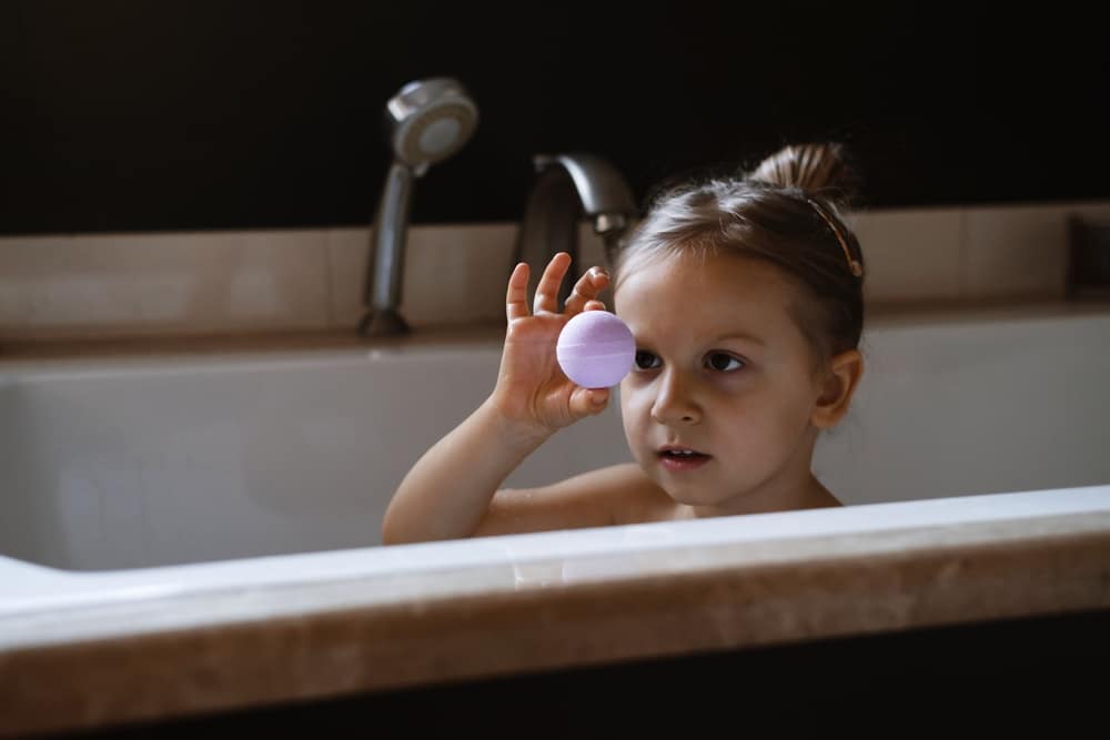 A view of a kid holding a bath bomb in shower
