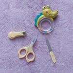 Manicure set for newborn care. Scissors, clipper and soother isolated on purple fabric background.