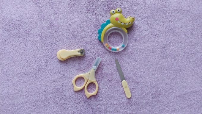 Manicure set for newborn care. Scissors, clipper and soother isolated on purple fabric background.