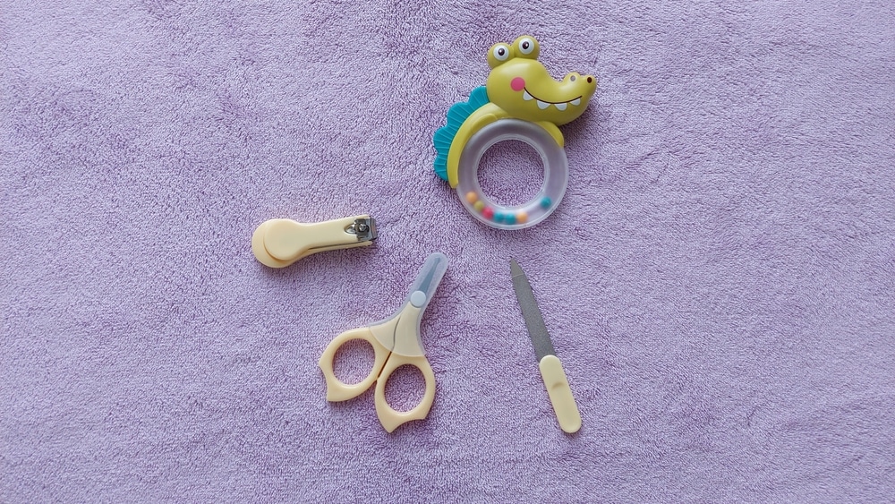 Manicure set for newborn care. Scissors, clipper and soother isolated on purple fabric background.