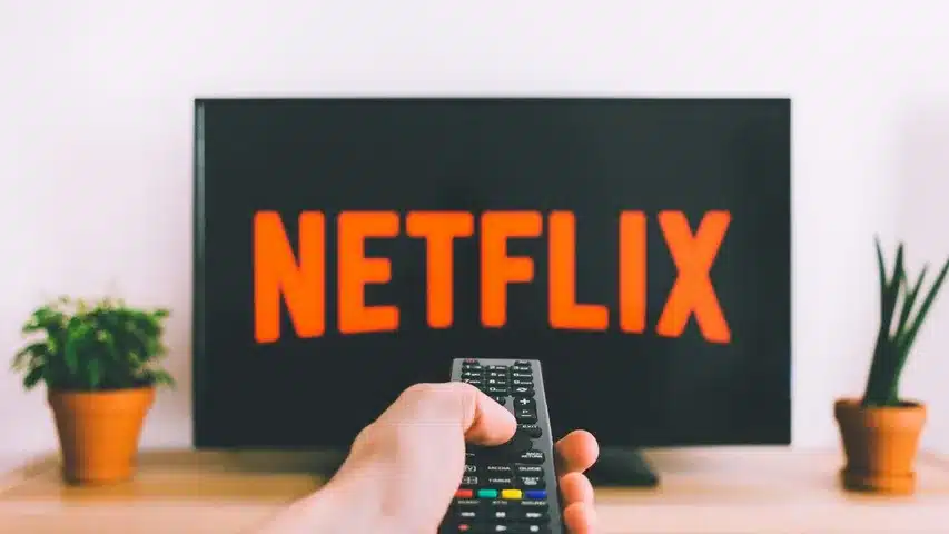 a hand holding remote, netflix on screen