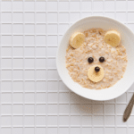 oatmeal porridge with fruit and berries. children's food with a bear face
