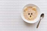 oatmeal porridge with fruit and berries. children's food with a bear face