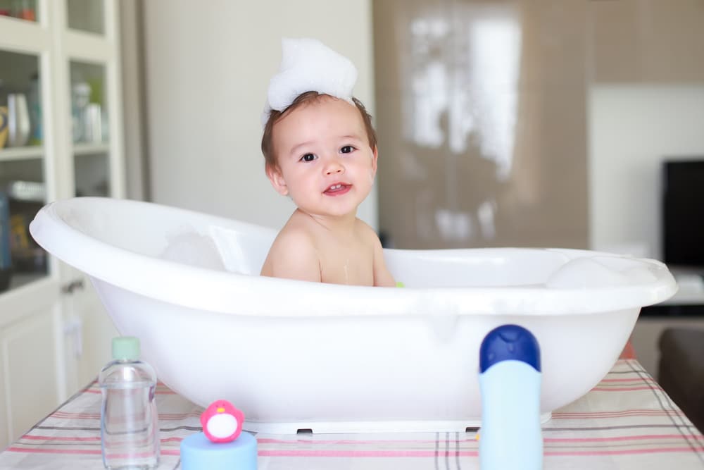Adorable cute baby take a bath and playing with foam bubbles with smiling face