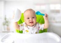 Baby Sitting At Table With Spoon Child Have A Meal