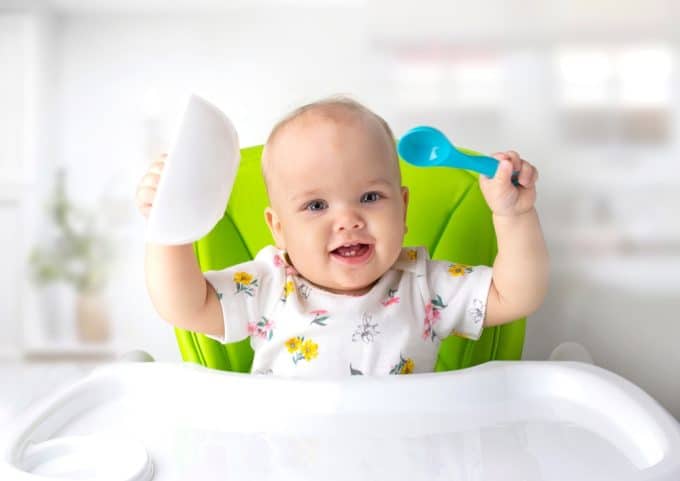 Baby Sitting At Table With Spoon Child Have A Meal
