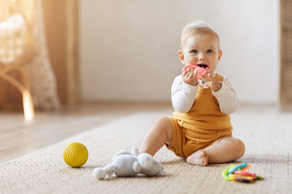 Portrait of smiling cute little child using colorful toys, chewing teether