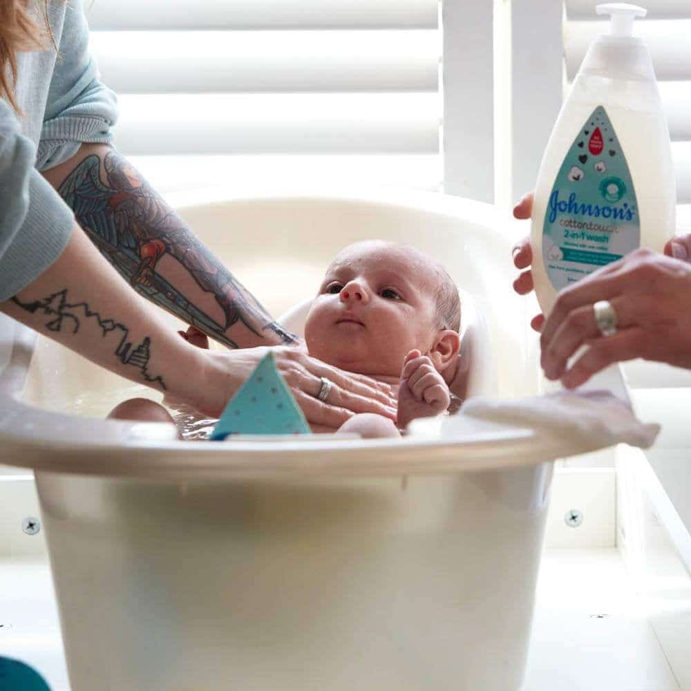 baby in a small bathtub mom giving her bath with Johnson s Baby Newborn Wash Shampoo