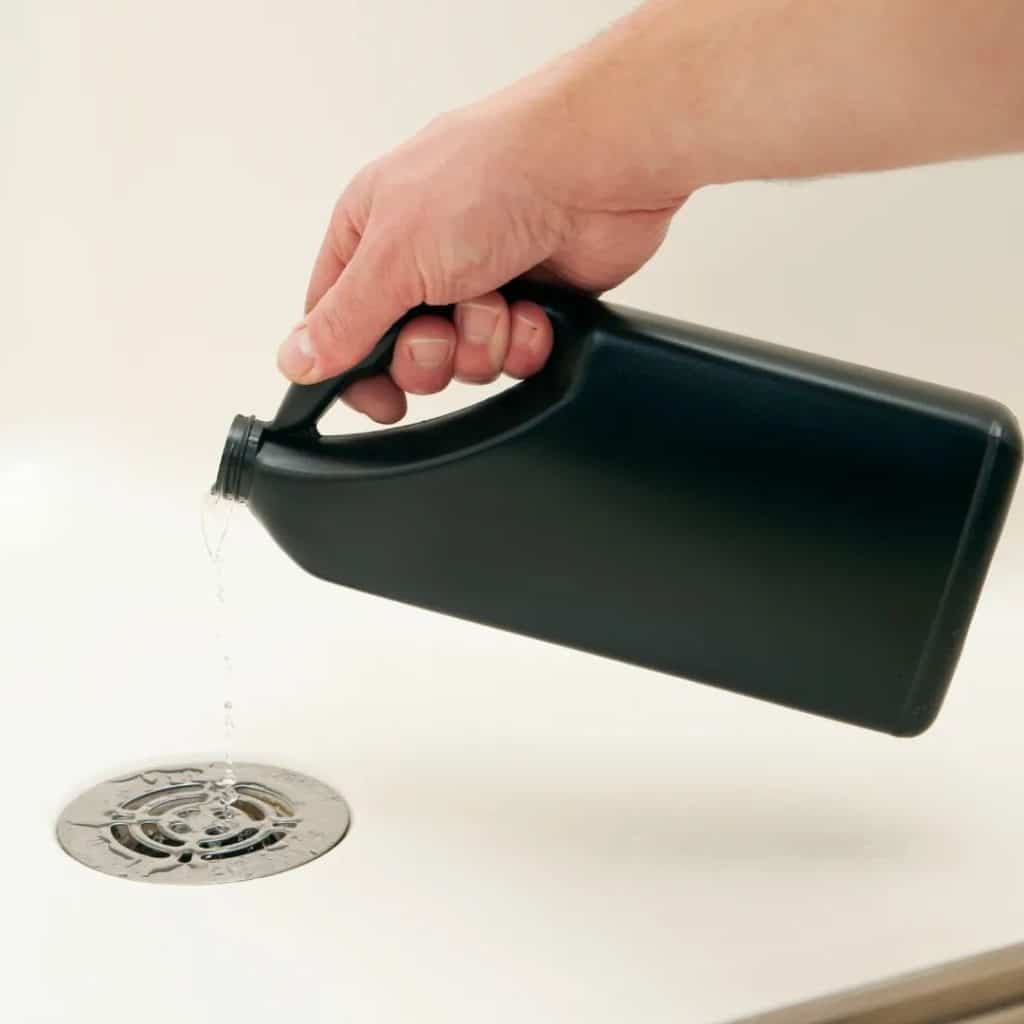 A view of a hand pouring cleaner into the drain
