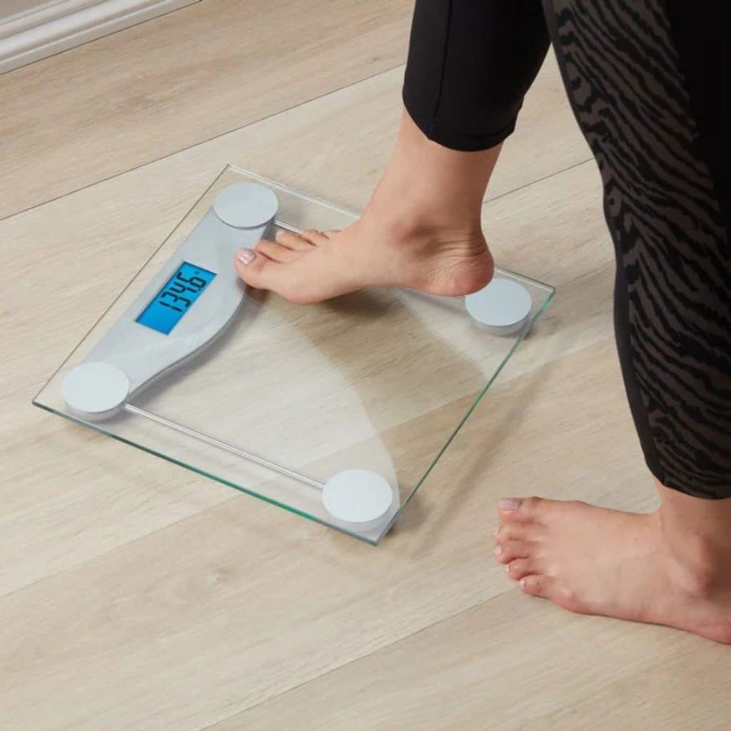 A view of a person setting one foot on the weighing scale