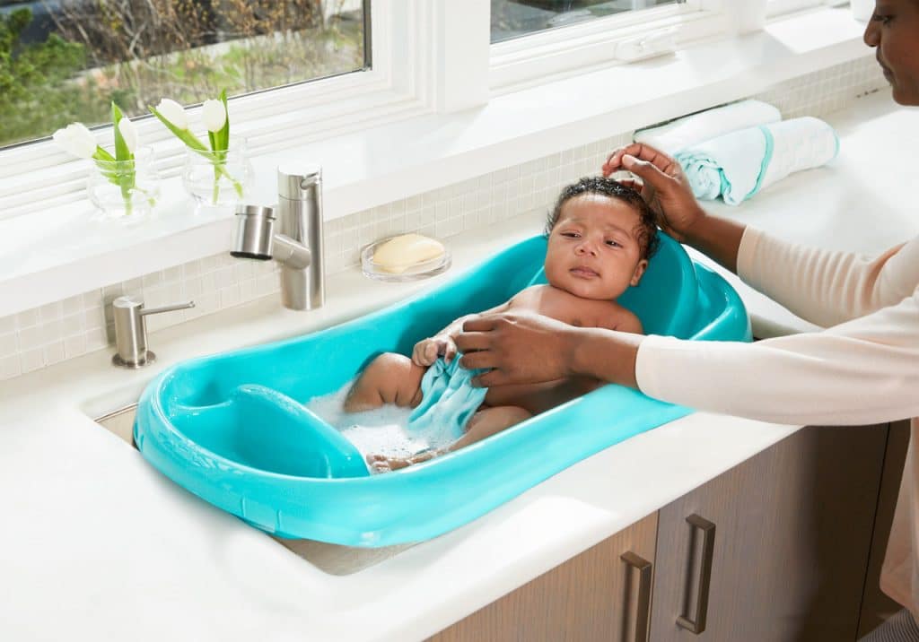 a baby in sink seat taking shower