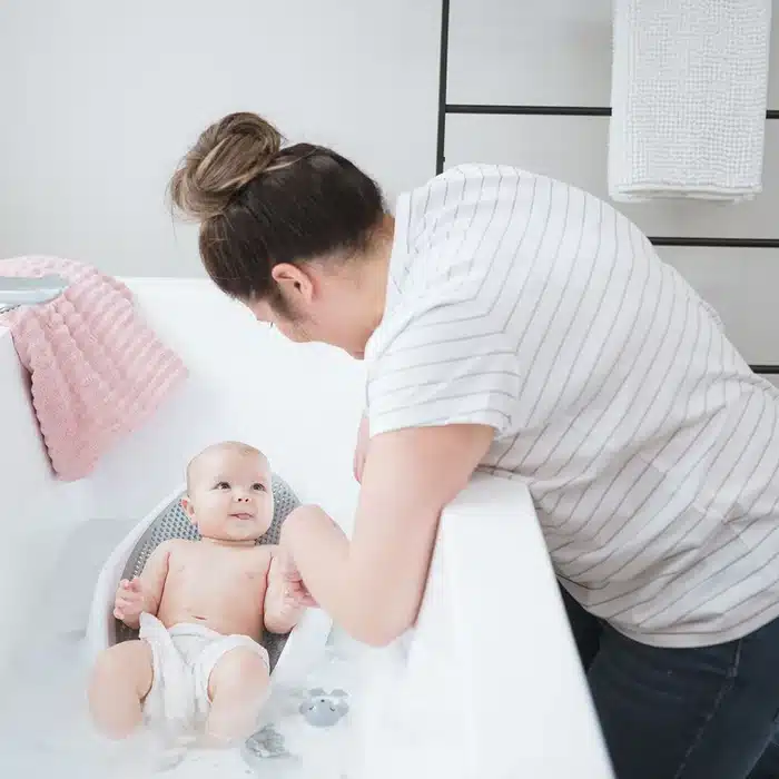a baby looking at mom and smiling while showering in Angelcare Baby Bath Support