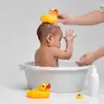 a baby sitting in a baby tub and showering