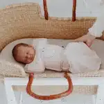 a baby sleeping in a wooden crib bassinet