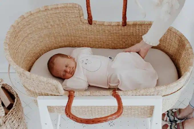 a baby sleeping in a wooden crib bassinet
