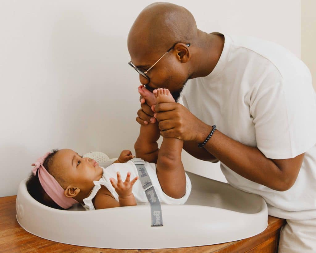 baby in a changing pad father holding her feet