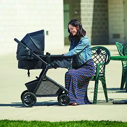 Mom smiling at her baby in a black stroller while sitting outdoors on a sunny day