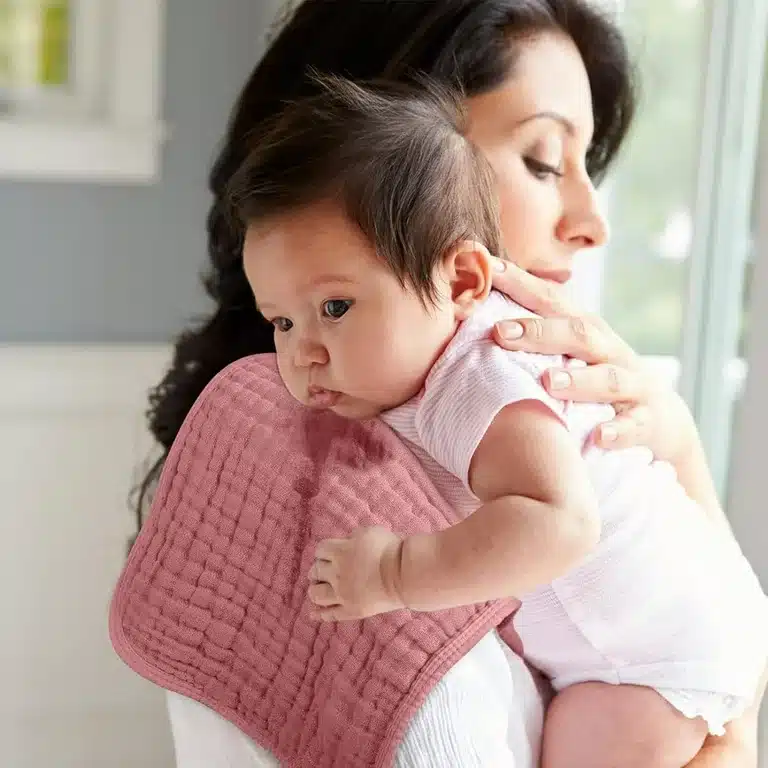 a mom carrying a baby Looxii Muslin Burp Cloth on her shoulder