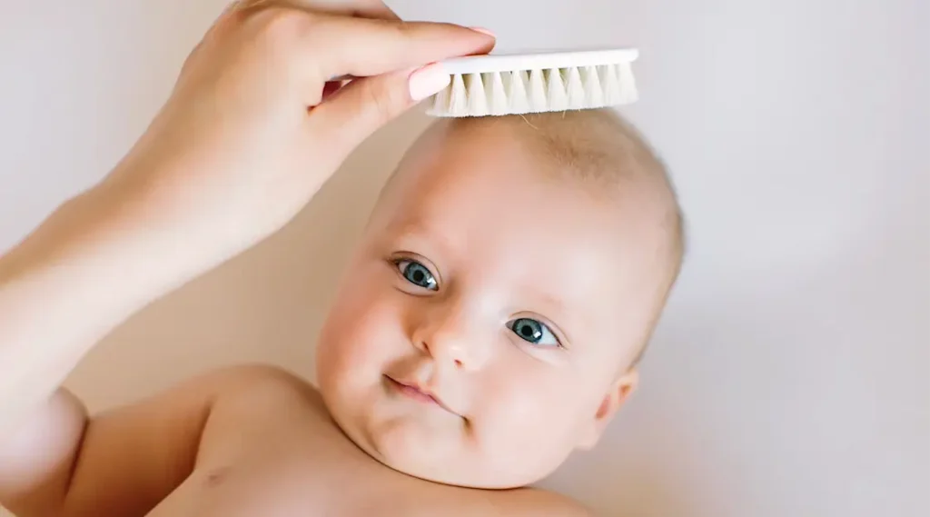 zoomed view of a moms hand combing baby s hair