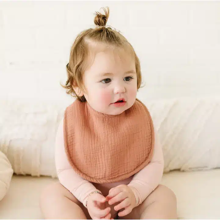 a baby girl wearing Konssy Muslin Baby Bib