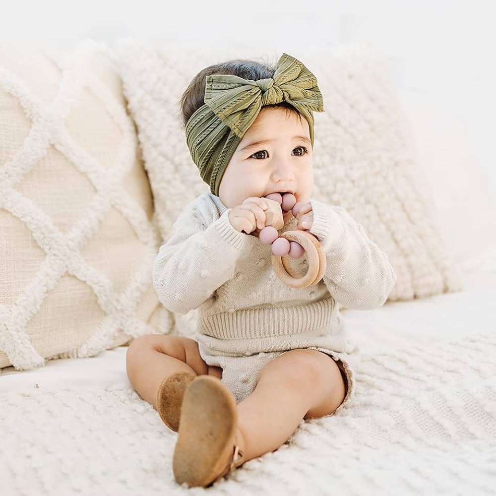a baby girl wearing Prohouse Headband chewing a teether