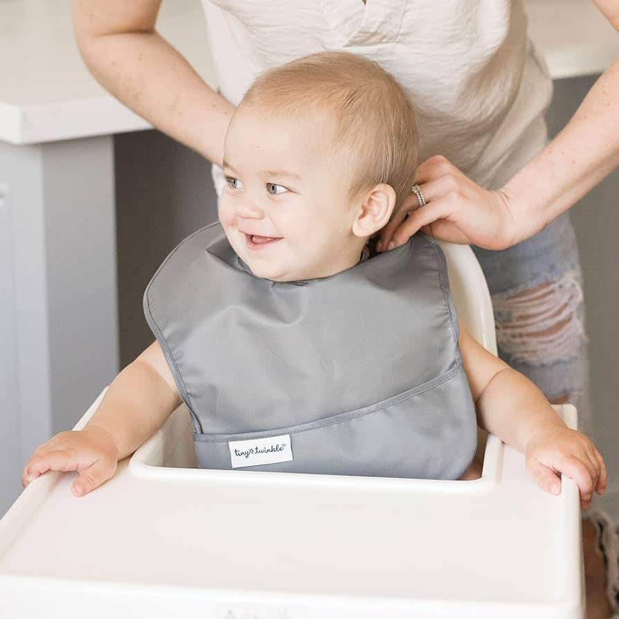 a bbay boy wearing Tiny Twinkle Mess Proof Bib and smiling