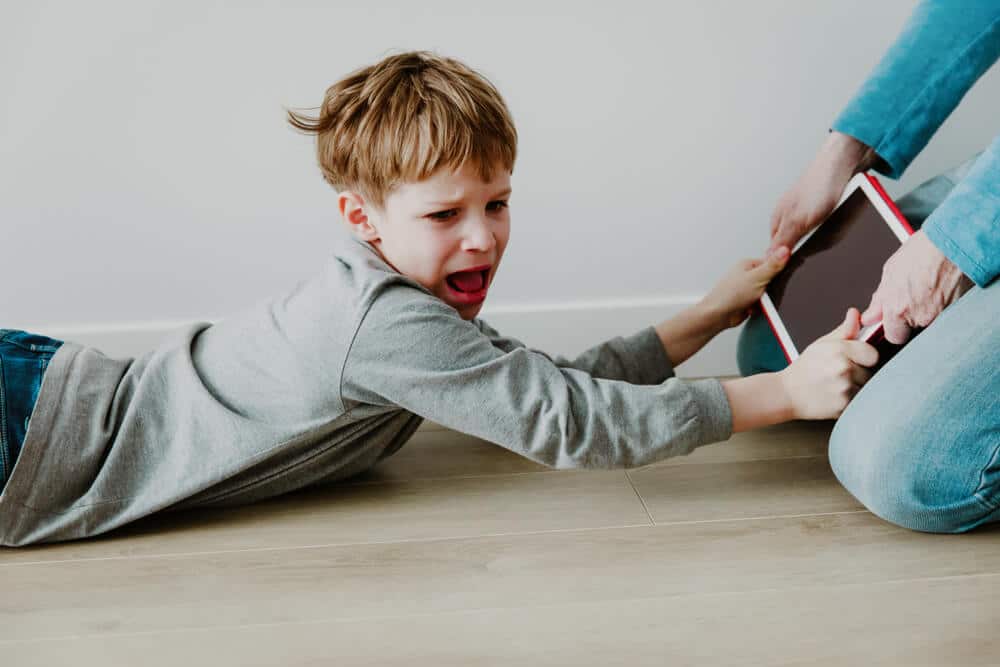 zoomed in view of hands snatching tablet from a kid
