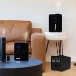 A modern living room with a black air purifier essential oil diffuser and a second air purifier in the background zon