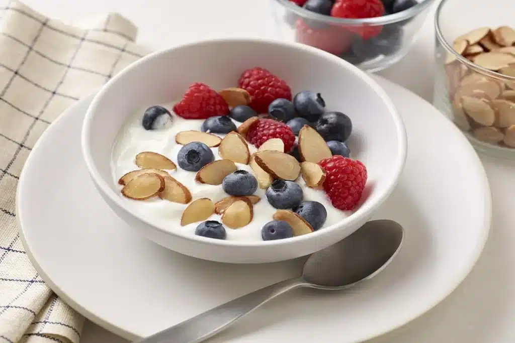 a bowl of greek yogurt with almonds strawberries
