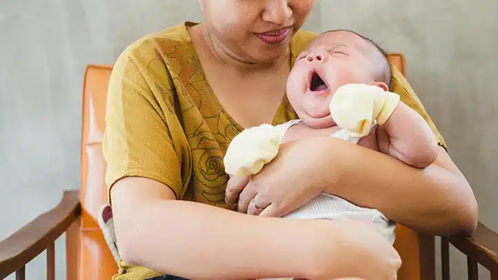 a mom holding her baby sitting on a chair