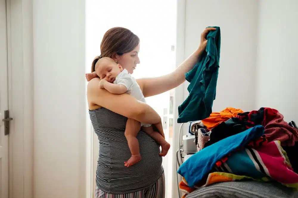 a mom holding her baby sorting through clothes
